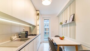 A modern kitchen with a built-in oven, a coffee machine, and a dining area with a table and chairs. - MoHost - Uno (Brasov)