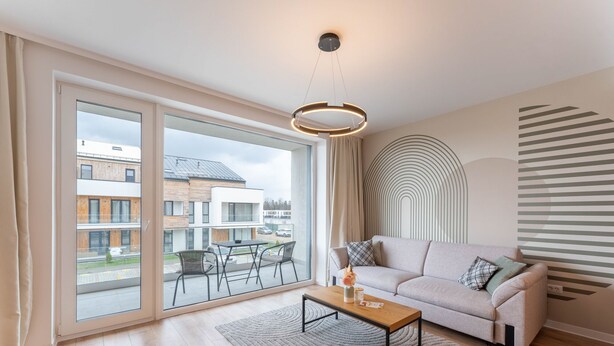 A modern living room with a sofa, a coffee table, and a large window with a view of buildings. - MoHost - Uno (Brasov)