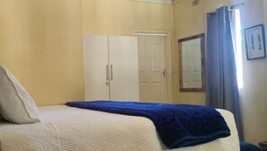 Ein Schlafzimmer mit Bett, Kissen, einem Schrank und einem Spiegel.