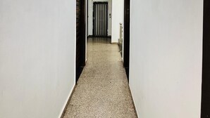 Un couloir aux murs blancs, au sol à motifs et doté d’un éclairage encastré.