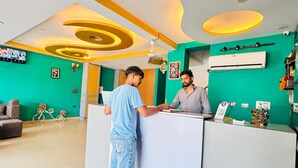 Un espace d’accueil au design moderne, agrémenté d’un mur végétal, d’un comptoir d’accueil blanc et d’un plafond orné de luminaires circulaires.