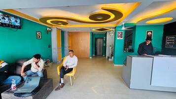 A reception area with a modern design, including a reception desk, a waiting area with a sofa and chairs, and a hallway leading to other parts of the building.