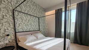 Ein modernes Schlafzimmer mit einem Himmelbett, einem kleinen Tisch und einer Wand mit Muster.