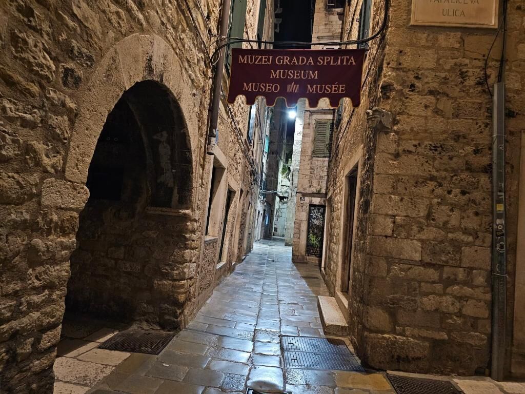 A narrow stone corridor with a sign for the Muzej Grada Splita Museum.