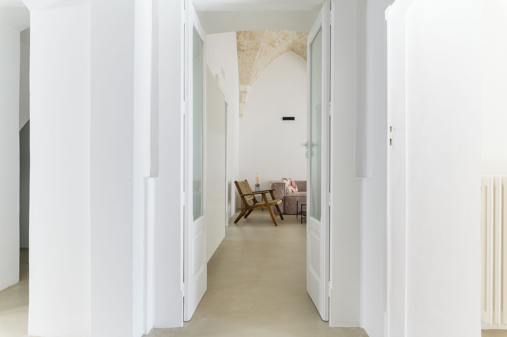Un pasillo con paredes blancas y piso color beige que conduce a una habitación con techo color beige.