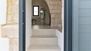 Eine Treppe führt zu einem Raum mit einer Steinwand, einem Fenster und einer Heizung.