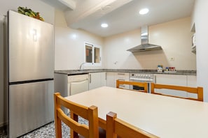 Cozinha compacta com geladeira de aço inoxidável, forno embutido, micro-ondas e janela sobre a pia.