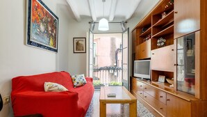 En stue med en rød sofa, et træskab med et fjernsyn og et lille bord.