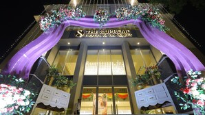 Fachada de hotel con un arco imponente, un letrero de bienvenida y arreglos florales decorativos.