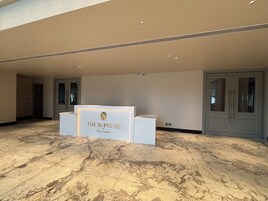 Un área de recepción con piso de mármol y un mostrador identificado como "The Supreme Hotel & Banquet".