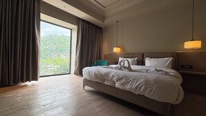 Habitación de hotel con una cama grande, vistas a zonas verdes y un diseño moderno.