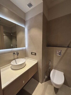 Ein modernes Badezimmer mit großem Spiegel, weißem Waschbecken und Toilette.