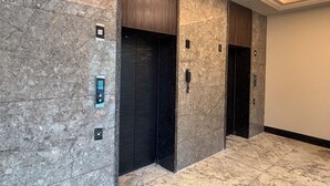 Un ascensor moderno con panel de control digital, pared texturizada y suelo de mármol.