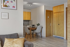 Un espace de vie compact comprenant un coin repas, une kitchenette et une porte en bois.