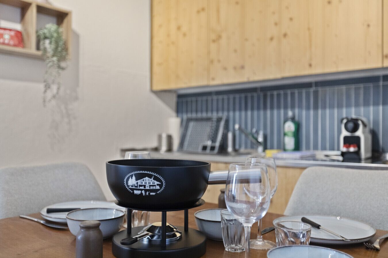 Une table à manger avec un saladier noir, des verres transparents, des assiettes et des couverts.