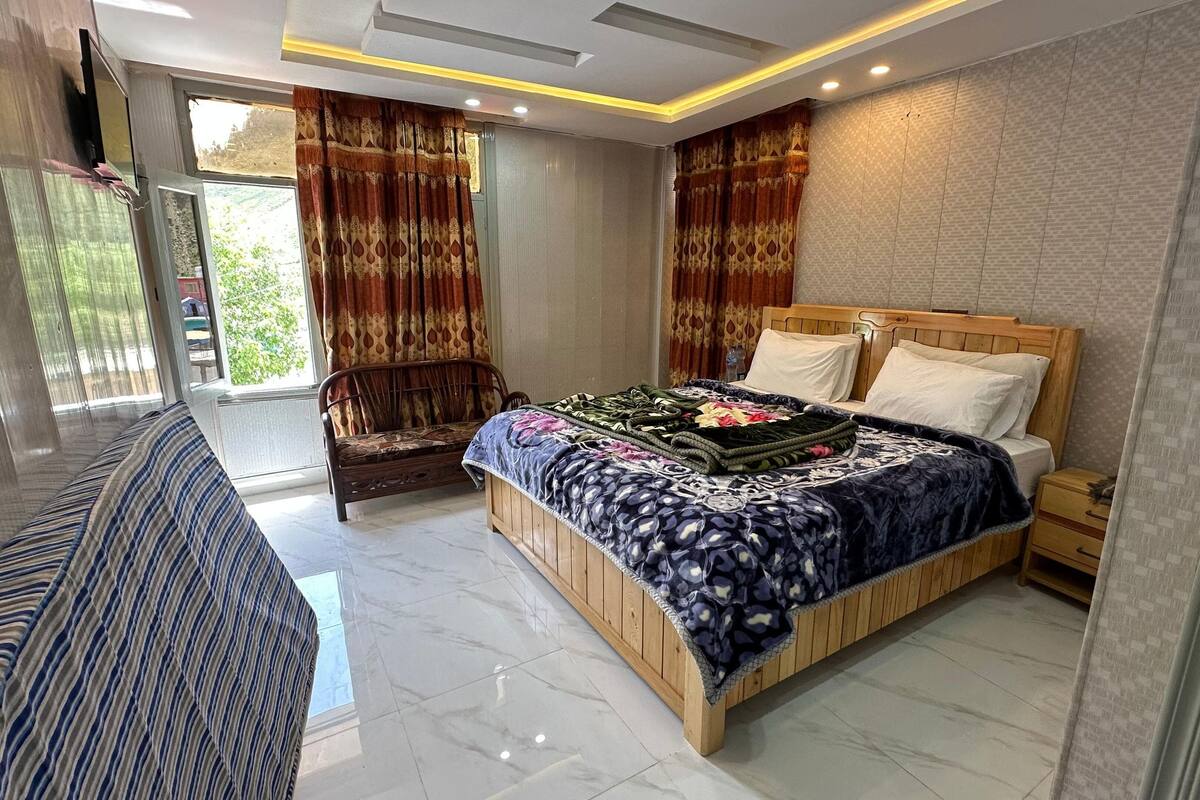 A modern bedroom with a large bed, a wooden nightstand, a bench, and a sofa.