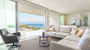 A modern living room with a large sliding glass door leading to a balcony with a view of the ocean. - Penthouse with ocean view / beach access at Mambo Beach (willemstad)