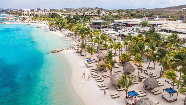 A beach resort with a sandy shoreline, palm trees, and a clear blue sea. - Penthouse with ocean view / beach access at Mambo Beach (willemstad)