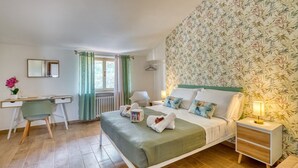 A bedroom with a bed, bedside table, chair, desk, and a window with curtains.