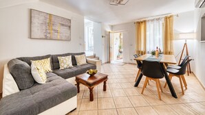 A living room with a sofa, coffee table, and dining area with chairs and a table.