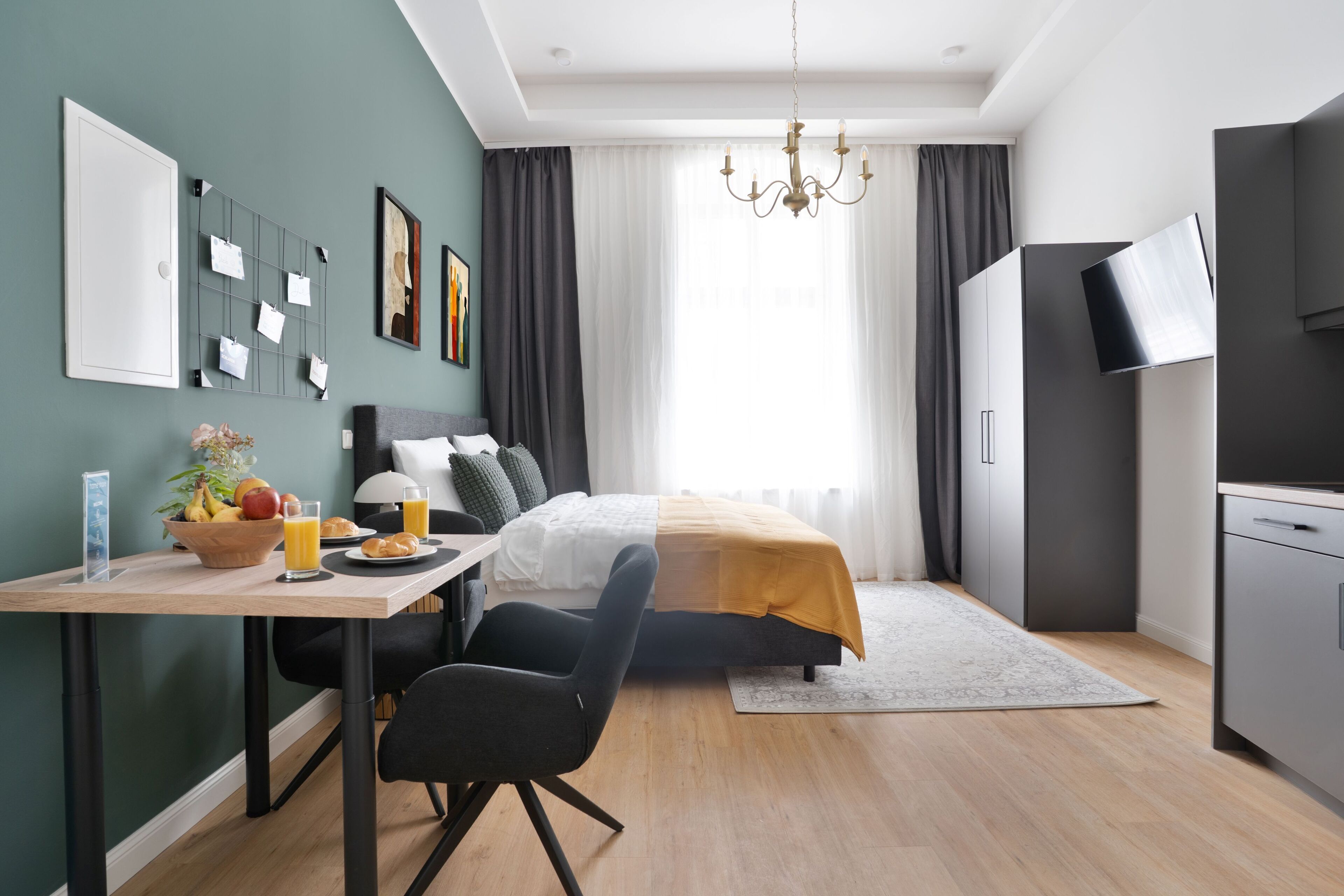 Ein modernes Hotelzimmer mit Bett, Schreibtisch mit Frühstück, Fernseher und Kleiderschrank.
