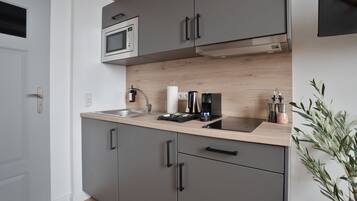 Een moderne keuken met grijze kastjes, een magnetron, een koffiezetapparaat en een spoelbak.