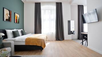 A modern bedroom with a bed, a desk, and a TV.