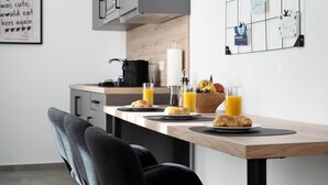 Eine moderne Küche mit Frühstücksecke, darunter Croissants, Saft und eine Schale Obst.