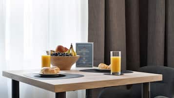 Ein Esstisch mit Croissants, einer Obstschale und einem Glas Orangensaft.