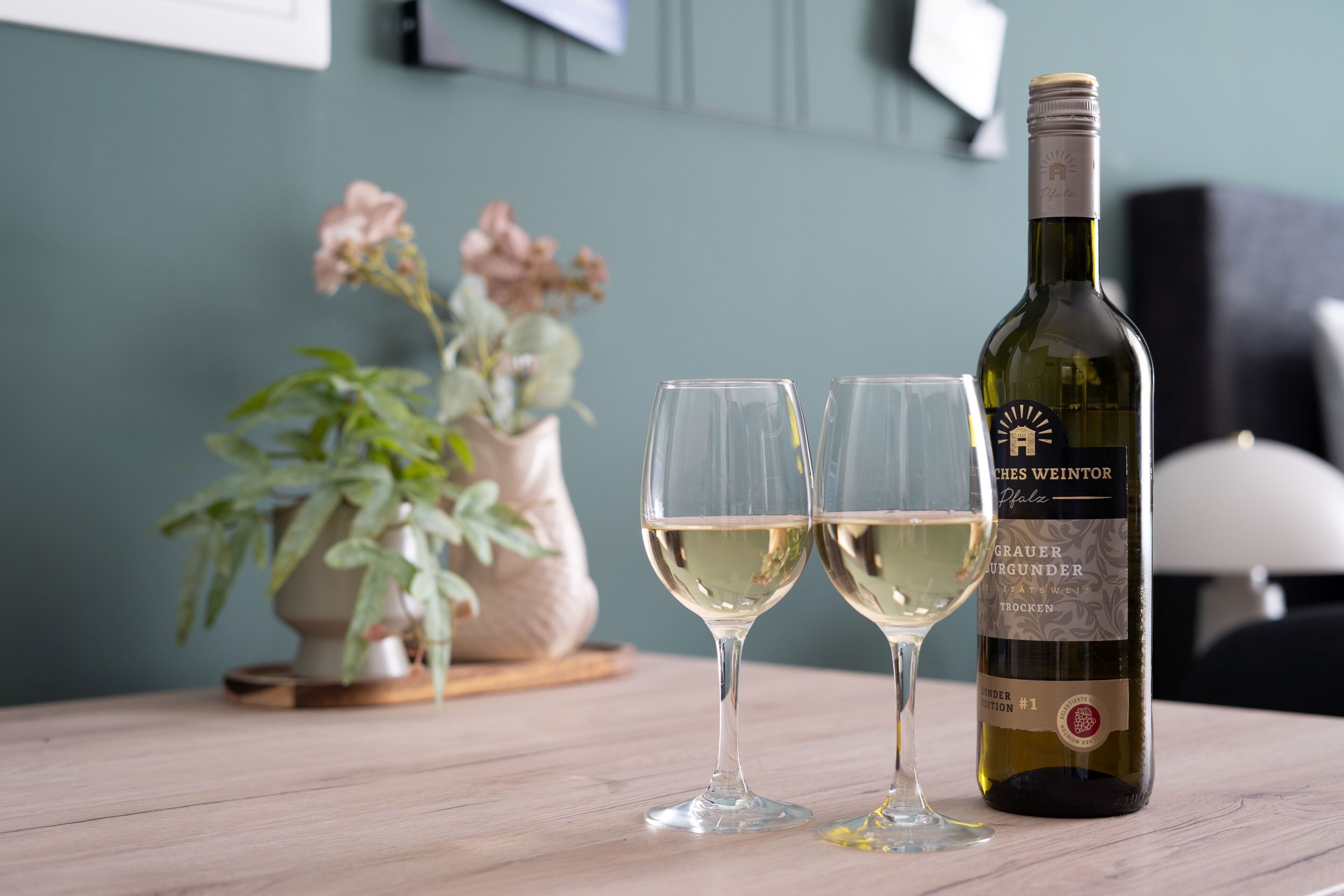 A bottle of wine and two glasses on a wooden table.