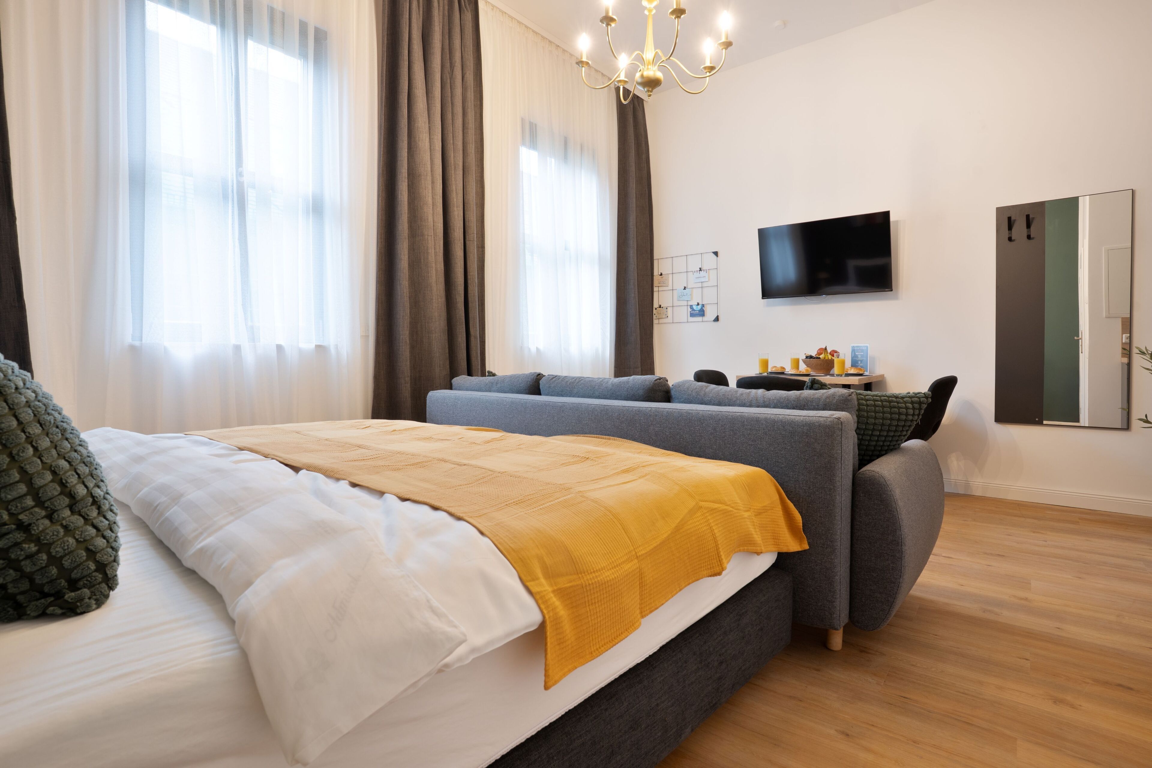 Ein modernes Hotelzimmer mit einem großen Bett, einer Couch, einem Fernseher und einem Kleiderschrank.