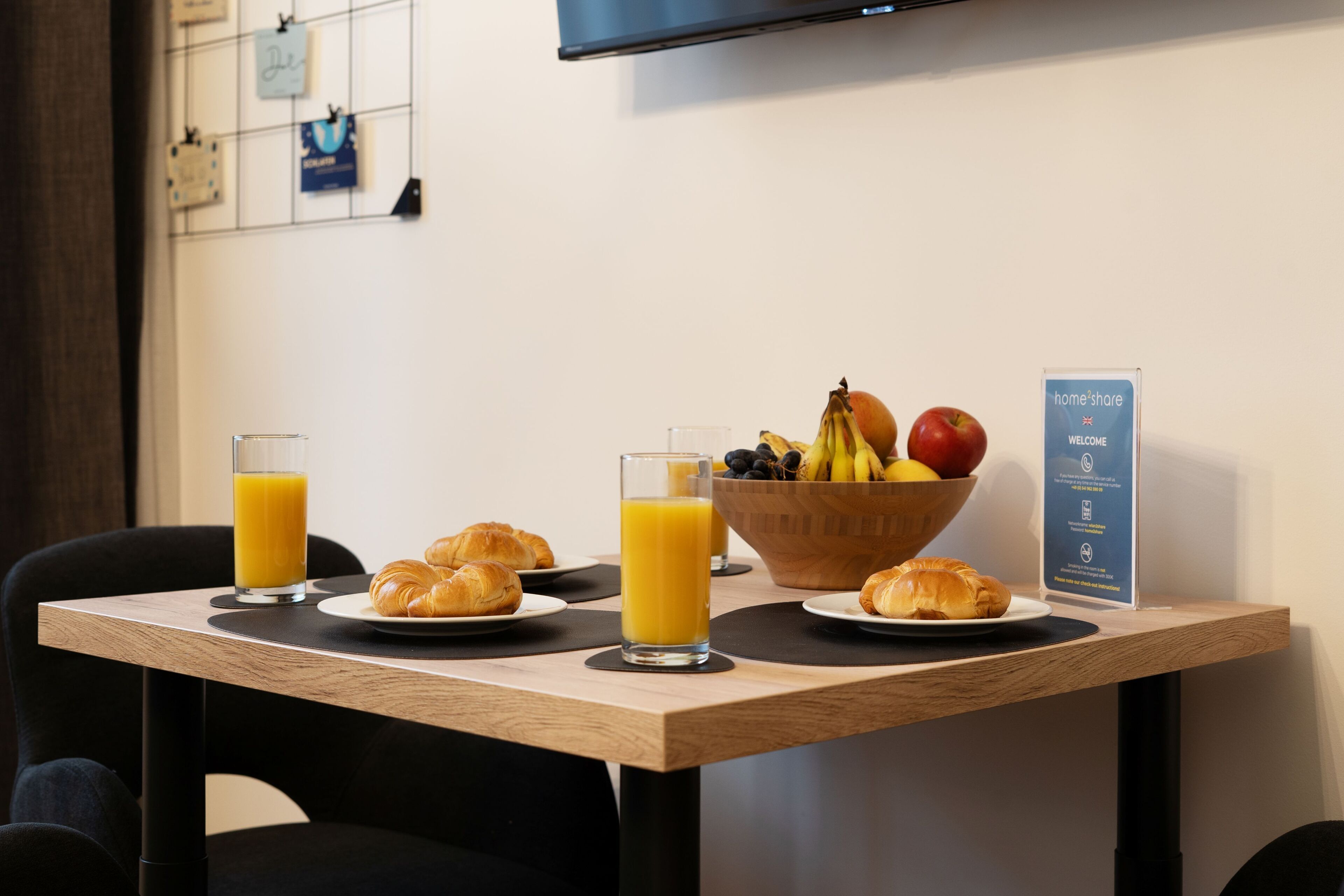 Ein Frühstückstisch mit Croissants, Obstschale und Orangensaftgläsern.