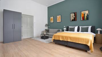 A modern bedroom with a bed, grey wardrobe, and artwork on the wall.