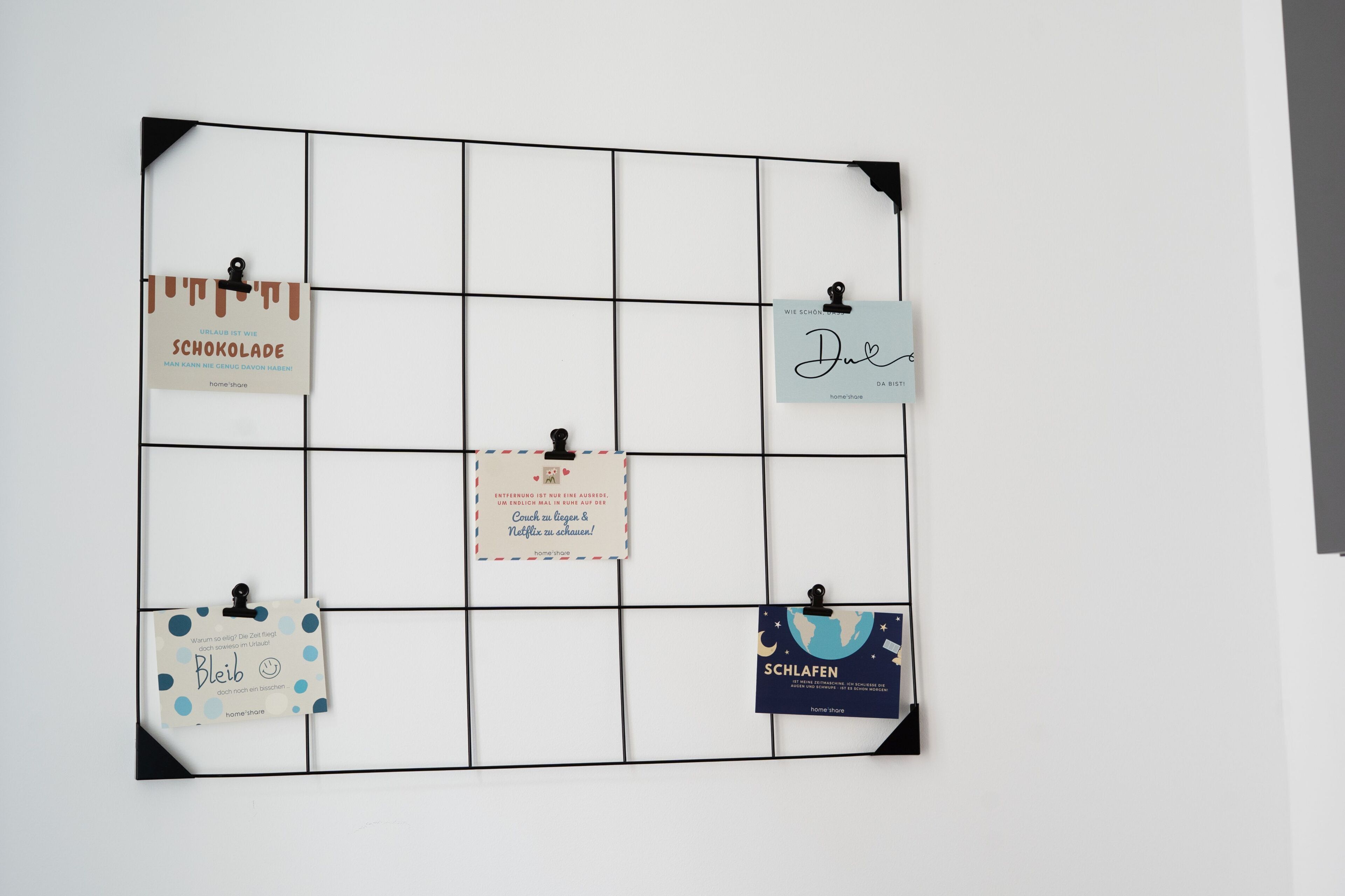 A wall with a grid of square sections, each holding a card with text and a clip.