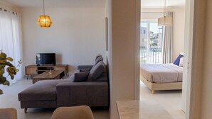 Una sala de estar moderna con un sofá, un televisor y una lámpara colgante.