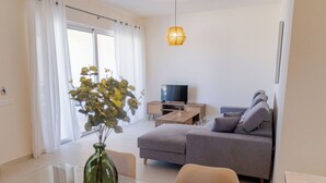 Una sala de estar moderna con un sofá, una mesa de centro, un televisor y un florero con plantas.