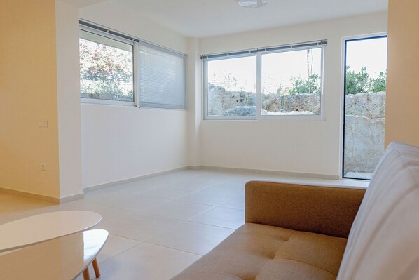 Habitación amplia con ventanas grandes, un sofá y una pequeña mesa.