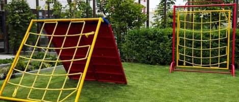A playground with two soccer goals and a climbing structure.