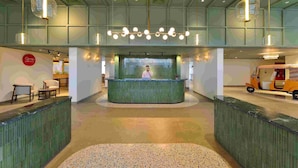 A reception area with a green counter, a receptionist, and a small seating area with chairs and a table. - Ginger Ekta Nagar, Statue of Unity (Garudeshwar)