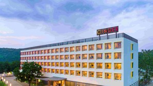 A multi-story hotel with a row of uniformly lit windows, a covered entrance, and a landscaped courtyard. - Ginger Ekta Nagar, Statue of Unity (Garudeshwar)