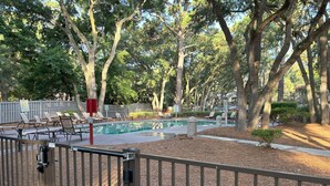 A pool area with lounge chairs and a fenced deck. - Driftwood Den - Walk to Folly Field Beach from Spacious 3BR/2.5BA Condo (Hilton Head Island)