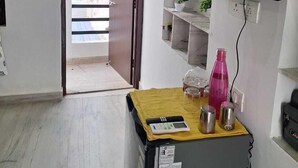 A compact kitchen with a wooden countertop, a refrigerator, and a TV mounted on the wall. - Tara Home Stay (Udaipur)