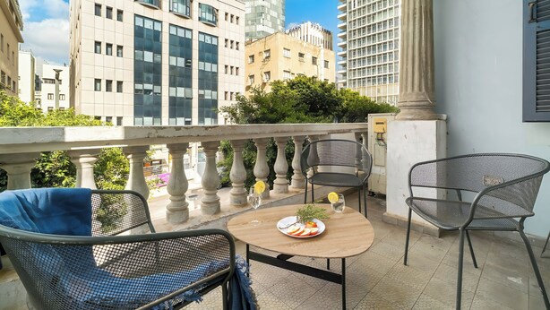 Ein Balkon mit Tisch, Stühlen und einer Schale Obst.