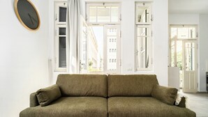 Ein grünes Sofa in einem Raum mit weißen Wänden und großen Fenstern.
