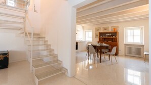 A spacious living area with a staircase, dining table, chairs, and a wooden cabinet. - Large Sunny Apartment in Verona - Sleeps 8 - Easy Free Parking (Parona)