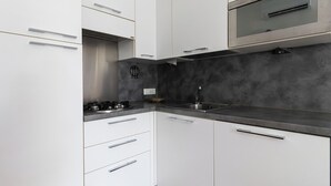 Eine moderne Küche mit weißen Schränken, einer Edelstahl-Spüle und einem Gasherd.