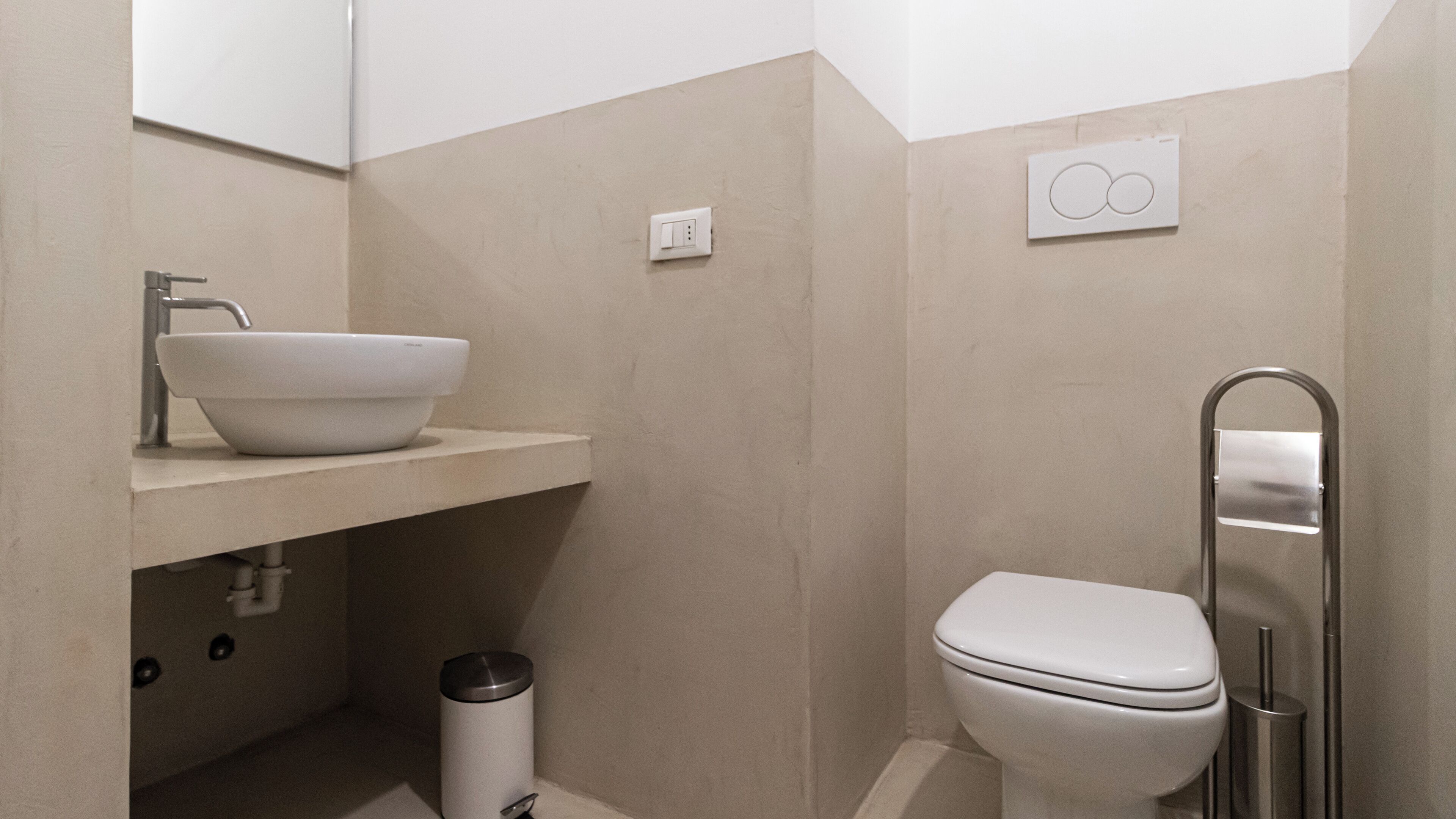 Un baño moderno con lavamanos, espejo y retrete blancos.