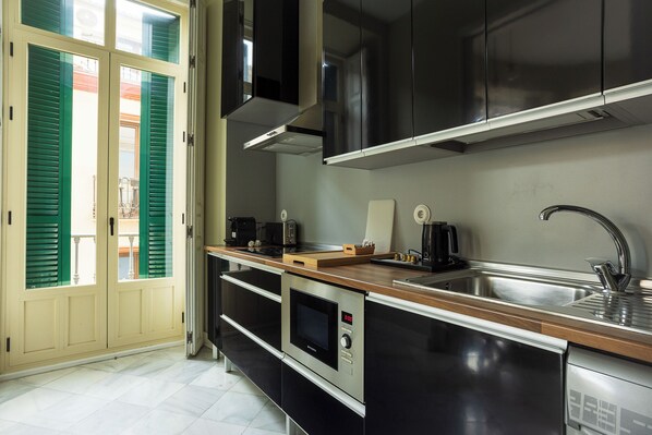 Una cocina moderna con electrodomésticos de acero inoxidable, una encimera de madera y un horno empotrado.