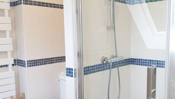 Une salle de bain moderne avec une douche à parois de verre, des toilettes blanches et des éléments décoratifs en carreaux bleus.