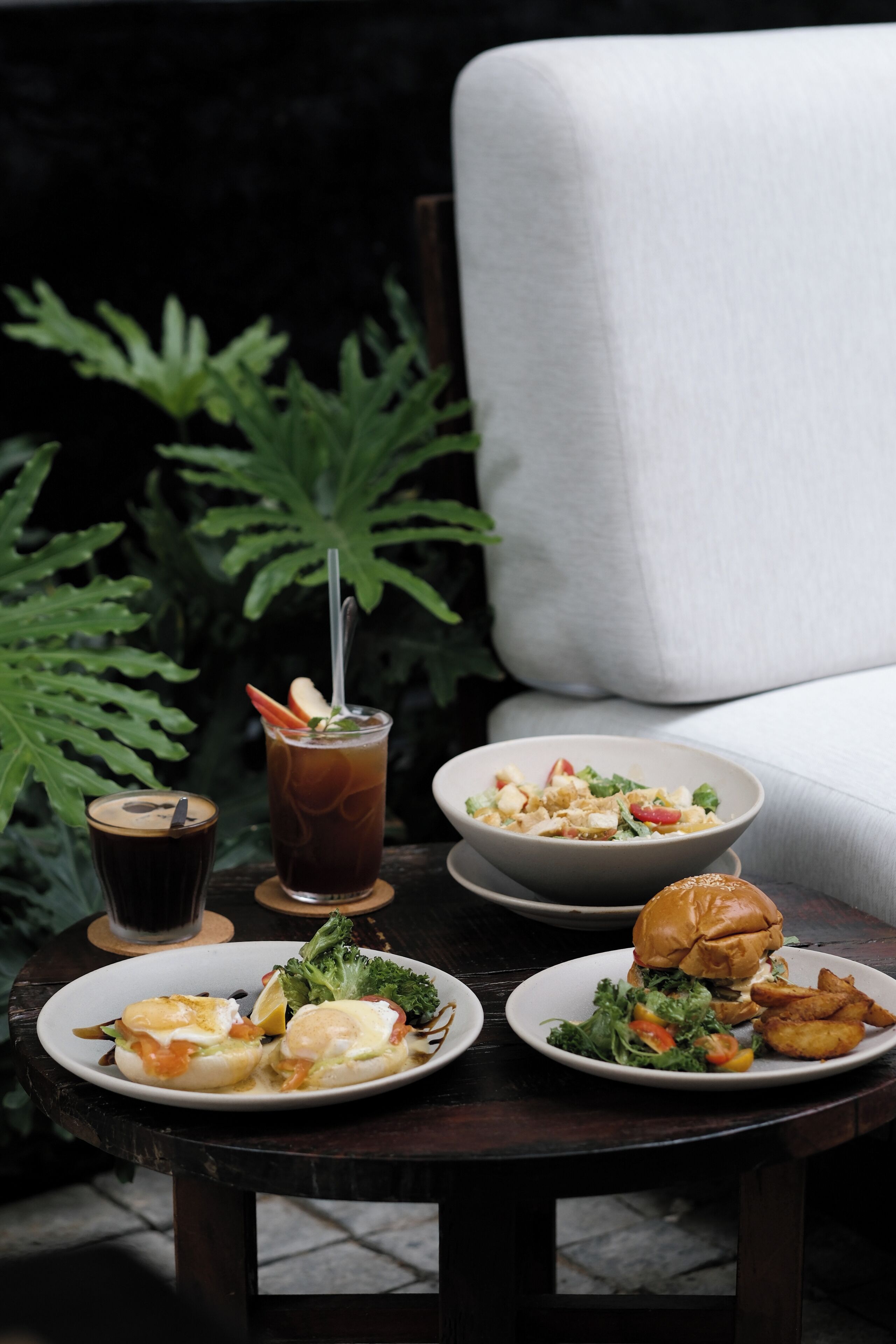 Una mesa con comida y bebidas, una silla y una planta al fondo.
